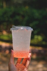 Close-up of a pink beverage in a plastic cup outdoors on a sunny day