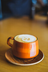 A warm cup of coffee on a saucer in a cafe setting.