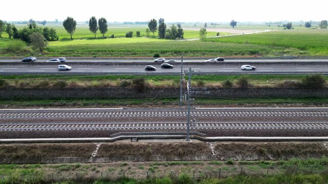 Europe, Italy , Milan 09,14,2024  - Frecciarossa Trenitalia  Hight speed 300km h train railway  view from the drone - the faster way to travel in Italy from Milan to Rome. A1 motorway , cars and train