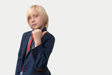 Portrait of young businessman with blond hair, dressed in blue suit and red tie, points a finger to the side isolated on white background.