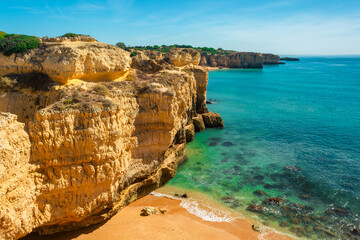 Yellow cliff rocks over sandy beach near Albufeira, Algarve region, Portugal, Europe. Popular touristic destination for summer vacation on Portuguese Atlantic coast