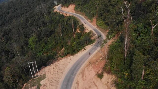 Aerial view of winding road through lush forest and serene mountains, Sam Neua, Laos.