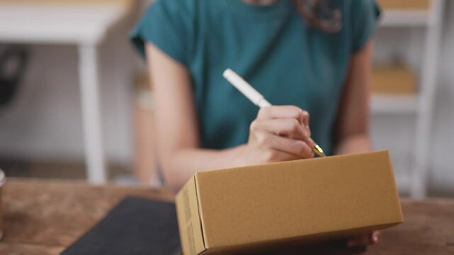 Business owner prepares a package for shipment in a warehouse, meticulously organizing details and logistics for timely delivery to a customer