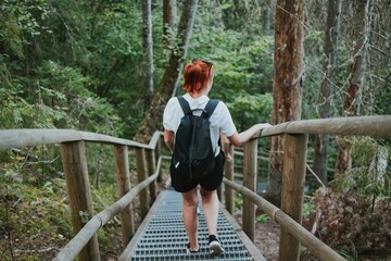 female hiker with a briefcase goes down the stairs with railings in the depths of the forest