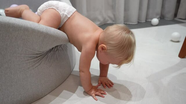 Curious baby girl climbs out of the pool with balloons and awkwardly falls on the floor and cries in the living room.