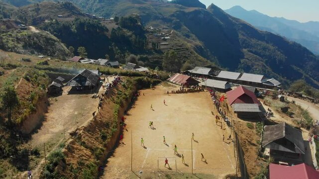 Aerial view of a scenic soccer field with players surrounded by mountains and clouds, Sin Ho, Lai Chau, Vietnam.