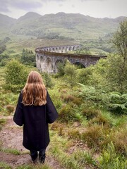 Jugendliches Mädchen im Kostüm vor dem Glenfinnan-Viadukt, Schottland