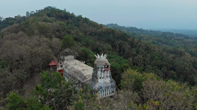Aerial view of the unique gereja ayam (chicken church) surrounded by lush greenery and forested hills, Yogyakarta, Indonesia.