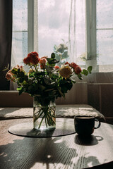 A bouquet of pink and white roses for the wedding anniversary for your beloved wife. A bouquet of flowers on the background of the window. A bouquet and a cup of coffee on the table