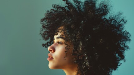 Close-up side profile of a young woman with voluminous curly hair, set against a minimalist background.