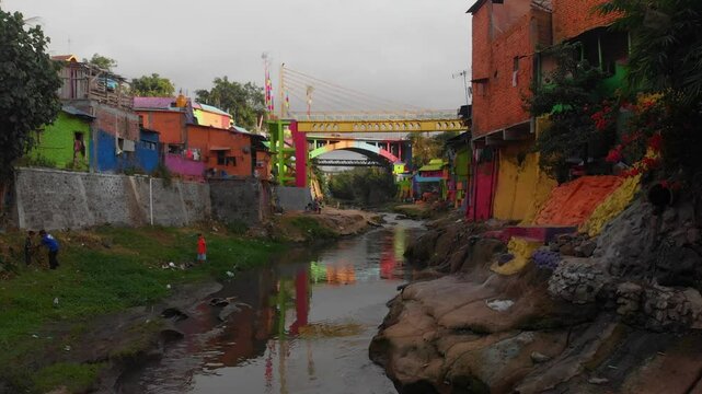 Aerial view of colourful houses and a bridge over a river in Jodipan, Malang City, East Java, Indonesia.