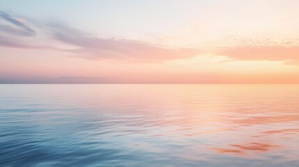 Fototapeta premium Early morning sunrise over a calm ocean, with soft pink and orange hues lighting up the sky.