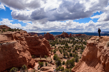 A solitary man stands on a cliff edge overlooking the stunning desert landscape of Kodachrome Basin State Park in Utah. Capturing the dramatic sky, colorful red rock formations and wilderness - USA