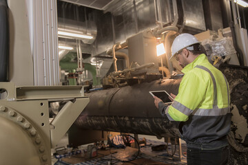 Engineer work in Industrial  chiller  HVAC heating ventilation air conditioning system and pipping line of industrial construction at boiler pump room system in the factory