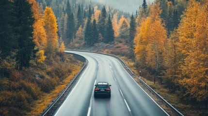 Fototapeta premium Car Driving on an Autumn Road Through a Scenic Mountain Landscape. Vibrant Fall Colors Surrounding the Highway as it Winds Through a Beautiful Forest, Capturing the Serenity of Nature During an Autumn