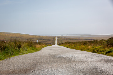 Fototapeta premium Committee road, Isle of north Uist on a quiet day with no other cars or traffic, well known for the birds of prey that can be seen along it