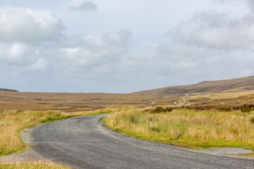 Fototapeta premium Committee road, Isle of north Uist on a quiet day with no other cars or traffic, well known for the birds of prey that can be seen along it
