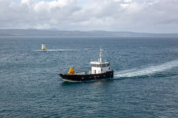 Small boat coming into port, Image shows a work boat with a crane returning to the harbour