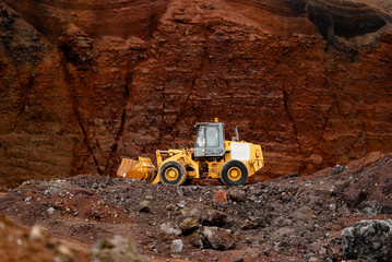 yellow tractor on a background of red sand or clay