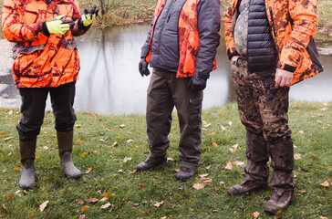 Three men's clothing during autumn hunting; various styles and boots. People are standing.