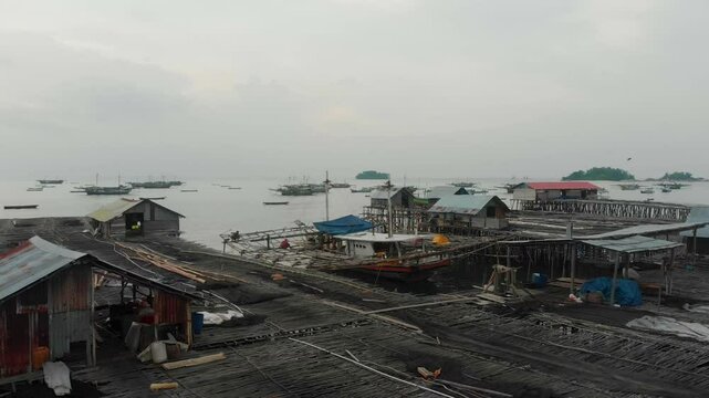 Aerial view of fishing boats at sunset near a coastal village by the sea, Tanjung Binga, Indonesia.