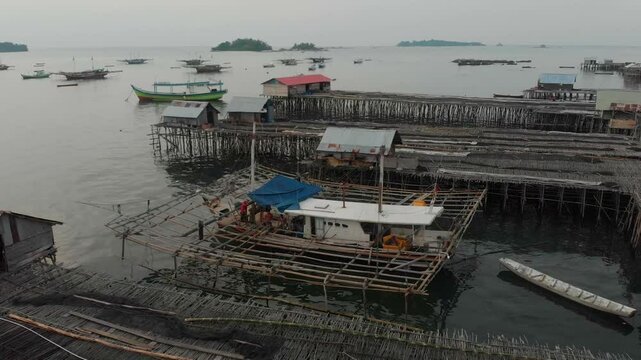 Aerial view of a tranquil fishing village with wooden structures and boats at sunset, Tanjung Binga, Indonesia.