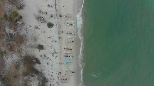 Aerial view of serene beach with traditional fishing boats along the tranquil sea, Manggar, Indonesia.