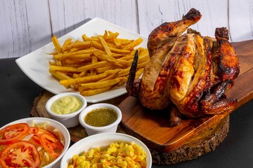 Deliciously charred and smoky Pollo a la Brasa (grilled chicken) served whole and in pieces, accompanied by crispy fries, fresh salad, and a flavorful dipping sauce. A classic Latin American dish, coo