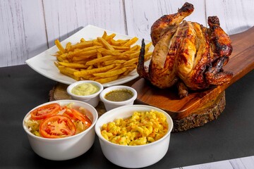 Deliciously charred and smoky Pollo a la Brasa (grilled chicken) served whole and in pieces, accompanied by crispy fries, fresh salad, and a flavorful dipping sauce. A classic Latin American dish, coo
