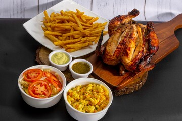 Deliciously charred and smoky Pollo a la Brasa (grilled chicken) served whole and in pieces, accompanied by crispy fries, fresh salad, and a flavorful dipping sauce. A classic Latin American dish, coo