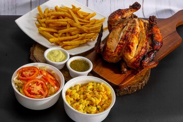Deliciously charred and smoky Pollo a la Brasa (grilled chicken) served whole and in pieces, accompanied by crispy fries, fresh salad, and a flavorful dipping sauce. A classic Latin American dish, coo