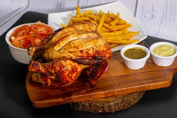 Deliciously charred and smoky Pollo a la Brasa (grilled chicken) served whole and in pieces, accompanied by crispy fries, fresh salad, and a flavorful dipping sauce. A classic Latin American dish, coo