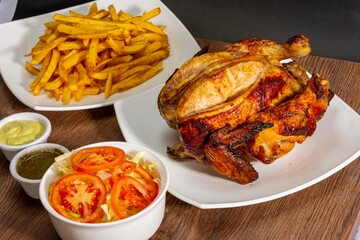 Deliciously charred and smoky Pollo a la Brasa (grilled chicken) served whole and in pieces, accompanied by crispy fries, fresh salad, and a flavorful dipping sauce. A classic Latin American dish, coo