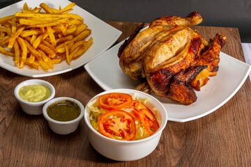 Deliciously charred and smoky Pollo a la Brasa (grilled chicken) served whole and in pieces, accompanied by crispy fries, fresh salad, and a flavorful dipping sauce. A classic Latin American dish, coo