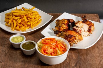 Deliciously charred and smoky Pollo a la Brasa (grilled chicken) served whole and in pieces, accompanied by crispy fries, fresh salad, and a flavorful dipping sauce. A classic Latin American dish, coo