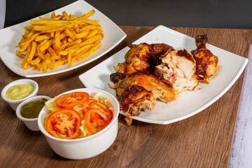 Deliciously charred and smoky Pollo a la Brasa (grilled chicken) served whole and in pieces, accompanied by crispy fries, fresh salad, and a flavorful dipping sauce. A classic Latin American dish, coo