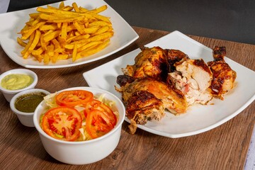 Deliciously charred and smoky Pollo a la Brasa (grilled chicken) served whole and in pieces, accompanied by crispy fries, fresh salad, and a flavorful dipping sauce. A classic Latin American dish, coo
