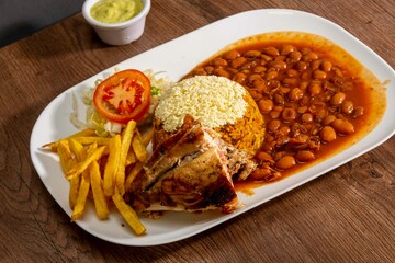 Deliciously charred and smoky Pollo a la Brasa (grilled chicken) served whole and in pieces, accompanied by crispy fries, fresh salad, and a flavorful dipping sauce. A classic Latin American dish, coo