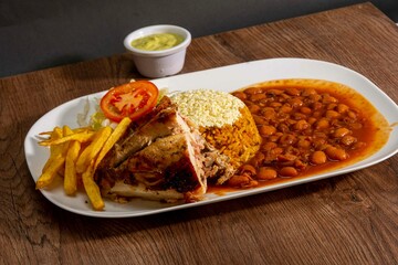 Deliciously charred and smoky Pollo a la Brasa (grilled chicken) served whole and in pieces, accompanied by crispy fries, fresh salad, and a flavorful dipping sauce. A classic Latin American dish, coo