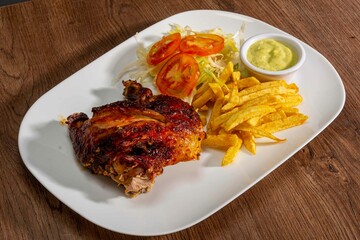 Deliciously charred and smoky Pollo a la Brasa (grilled chicken) served whole and in pieces, accompanied by crispy fries, fresh salad, and a flavorful dipping sauce. A classic Latin American dish, coo