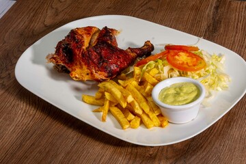 Deliciously charred and smoky Pollo a la Brasa (grilled chicken) served whole and in pieces, accompanied by crispy fries, fresh salad, and a flavorful dipping sauce. A classic Latin American dish, coo