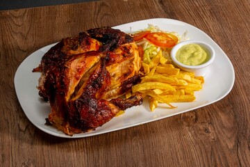 Deliciously charred and smoky Pollo a la Brasa (grilled chicken) served whole and in pieces, accompanied by crispy fries, fresh salad, and a flavorful dipping sauce. A classic Latin American dish, coo