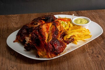 Deliciously charred and smoky Pollo a la Brasa (grilled chicken) served whole and in pieces, accompanied by crispy fries, fresh salad, and a flavorful dipping sauce. A classic Latin American dish, coo