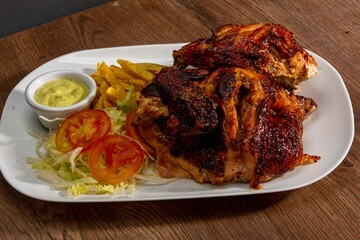 Deliciously charred and smoky Pollo a la Brasa (grilled chicken) served whole and in pieces, accompanied by crispy fries, fresh salad, and a flavorful dipping sauce. A classic Latin American dish, coo
