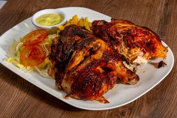 Deliciously charred and smoky Pollo a la Brasa (grilled chicken) served whole and in pieces, accompanied by crispy fries, fresh salad, and a flavorful dipping sauce. A classic Latin American dish, coo