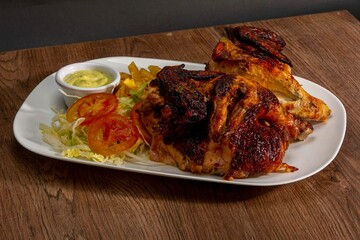 Deliciously charred and smoky Pollo a la Brasa (grilled chicken) served whole and in pieces, accompanied by crispy fries, fresh salad, and a flavorful dipping sauce. A classic Latin American dish, coo