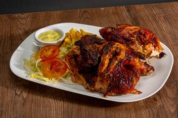 Deliciously charred and smoky Pollo a la Brasa (grilled chicken) served whole and in pieces, accompanied by crispy fries, fresh salad, and a flavorful dipping sauce. A classic Latin American dish, coo