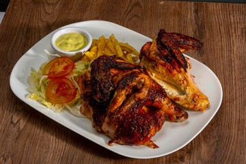 Deliciously charred and smoky Pollo a la Brasa (grilled chicken) served whole and in pieces, accompanied by crispy fries, fresh salad, and a flavorful dipping sauce. A classic Latin American dish, coo