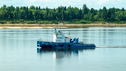 A large river vessel pulls two barges loaded with timber down the river