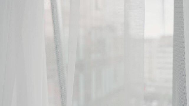 A pair of hands gently opening blue curtains to let in natural light, creating a calm ambience. Invokes feelings of serenity and new beginnings. Ideal for concepts related to awakening, privacy,